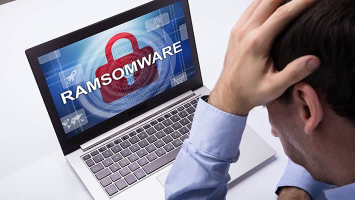 Worried Businessman Looking At Laptop With Ramsomware Word On The Screen At The Workplace